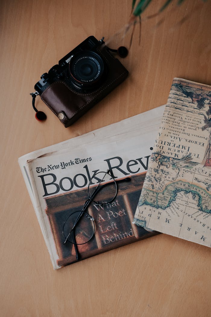 our-story Flat lay of vintage camera, map, and book review on wooden surface.